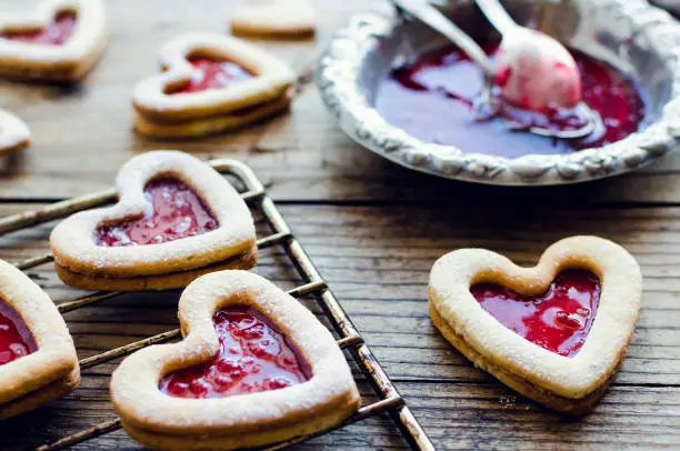 Heart shaped Linzer cookies with jam for Valentine's day. Delicious homemade pastry. Baking with love concept.