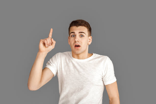 istock Copy Space for Text or Product. Young man standing isolated on grey pointing up solution illuminated 1200416250