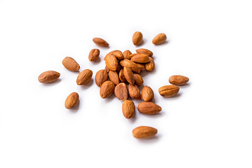 pile of roasted organic almonds with the peel isolated on a white background.