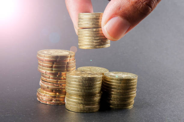 istock Hand put coins to stack of coins on black background 1200419707