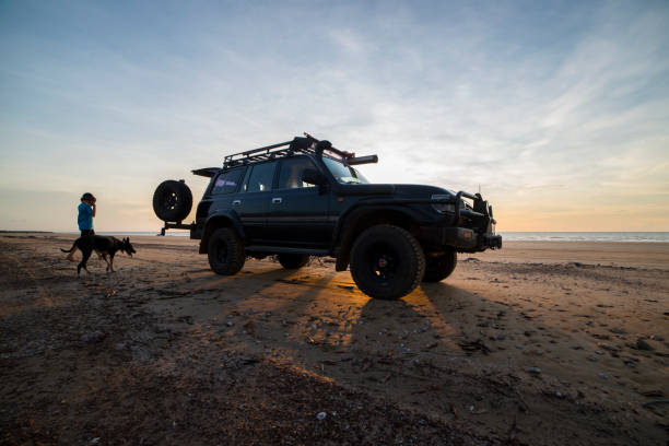 toyota landcruiser 80 series suv or 4x4 on the beach with sun setting behind the car. - darwin northern territory australia beach imagens e fotografias de stock