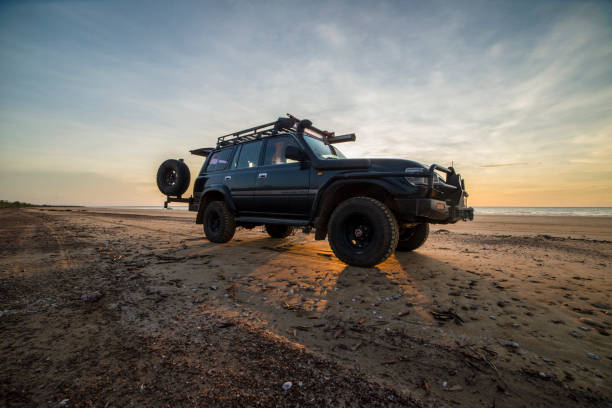 toyota landcruiser 80 serie suv oder 4x4 am strand mit sonnenuntergang hinter dem auto. - darwin northern territory australia sunset stock-fotos und bilder