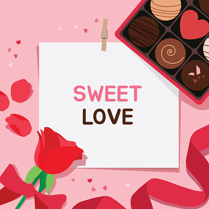 Valentine's Day background. Box of chocolate, confetti, petal and a rose tied with a red ribbon on pastel pink background with clipped paper card. Copy space. Flat lay top view composition.