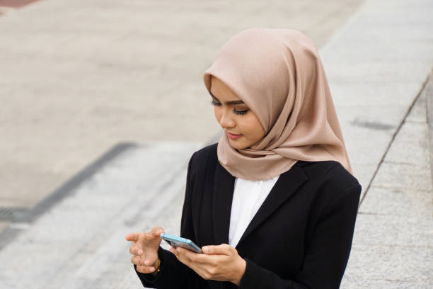 istock Beautiful asian muslim woman multitasking with her mobile device 1200426262
