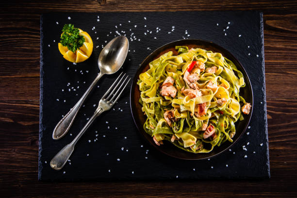 istock Pasta with salmon and vegetables on wooden background 1200426580