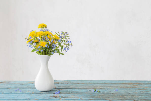 istock dandelions and forget-me-not in vase on background old wall 1200444681