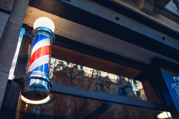 polo de barbero en una pared de barbería por la noche en una calle de barcelona, españa - barbers pole fotografías e imágenes de stock