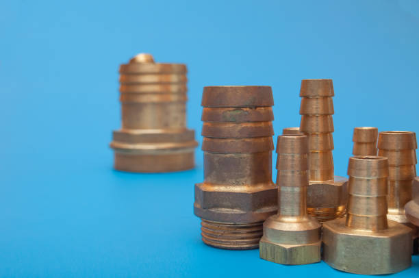Brass adapters of different diameters for hose and threaded connections. Equipment for agriculture and watering. Photo on a blue background.