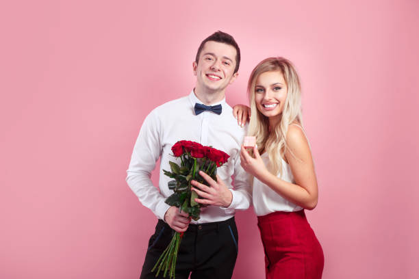 istock Attractive couple looking at camera and holding flowers 1200460564