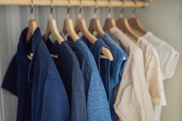 istock Clothes on hangers in the cabinet gradient from white to dark blue 1200460891
