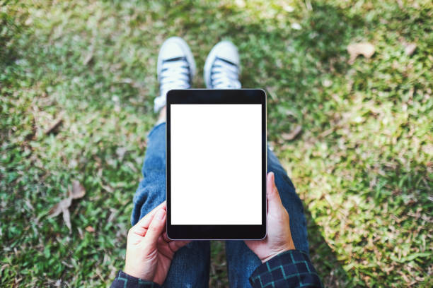 istock a woman holding and using black tablet pc with blank white desktop screen while sitting in the outdoors 1200461079