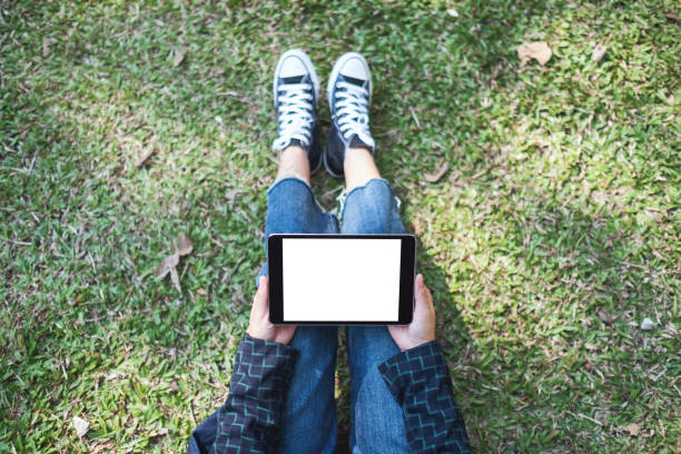 istock a woman holding and using black tablet pc with blank white desktop screen while sitting in the outdoors 1200461080