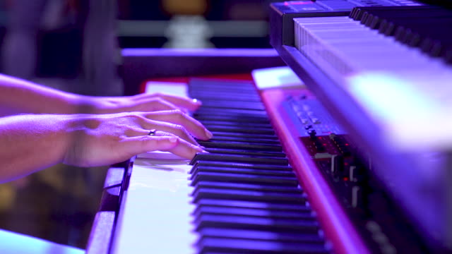Close up of hands on keyboard playing piano in slow motion.