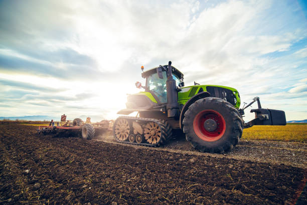 istock Modern tractor working on the farm,  tractor on cloudy sky background, agricultural machine. 1200463858