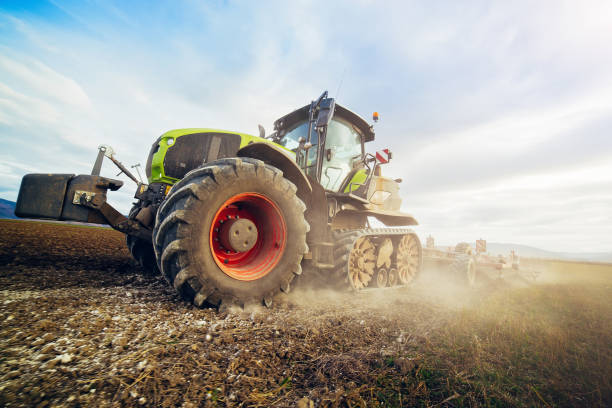 istock Modern tractor working on the farm,  tractor on cloudy sky background, agricultural machine. 1200463861