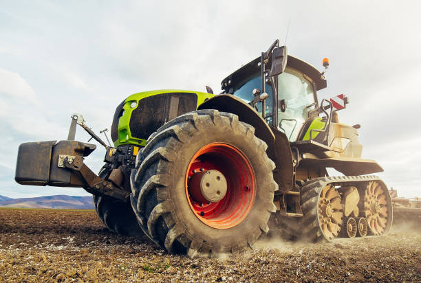 istock Modern tractor working on the farm,  tractor on cloudy sky background, agricultural machine. 1200463863