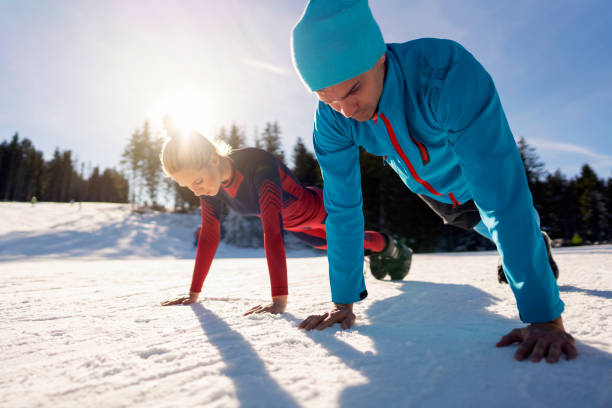 Young man and woman warming up before skiing on the mountain.