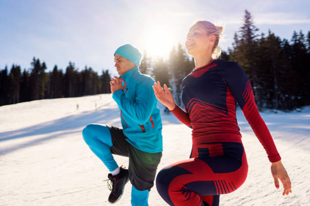 Young man and woman warming up before skiing on the mountain.