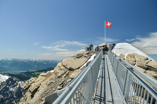 Glacier 3000, Switzerland - June 8, 2019: People enjoying beautiful views from viewing platform at the end of supension bridge on Scex Rouge peak in Glacier 3000 resort during June 2019