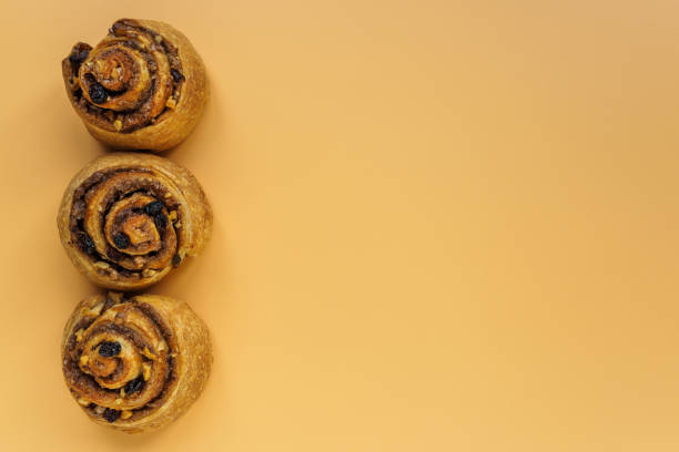 istock Cinnamon, nut and raisin buns on orange background with copy space 1200469415