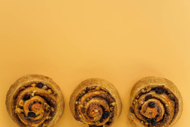istock Cinnamon, raisin and nut buns on orange background with copy space 1200469416