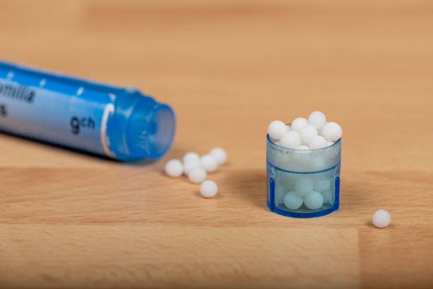 Paris, France - November 27, 2019 : Homeopathic globules scattered around with their colored containers in the shape of tube. Homeopathy delisted by the French social insurance in 2020
