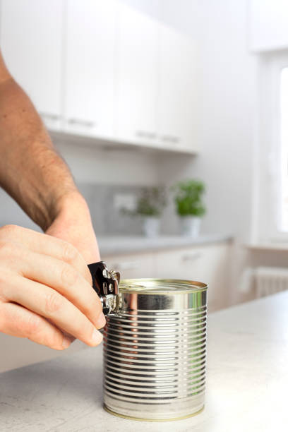 istock Hands of a man opening a can in a white kitchen 1200474371