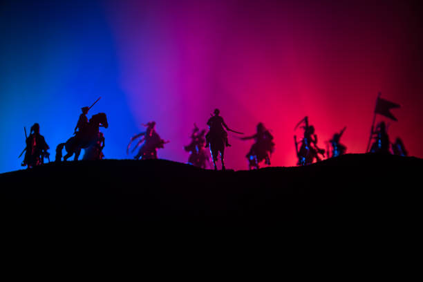 istock Medieval battle scene with cavalry and infantry. Silhouettes of figures as separate objects, fight between warriors on dark toned foggy background. Night scene. 1200475048