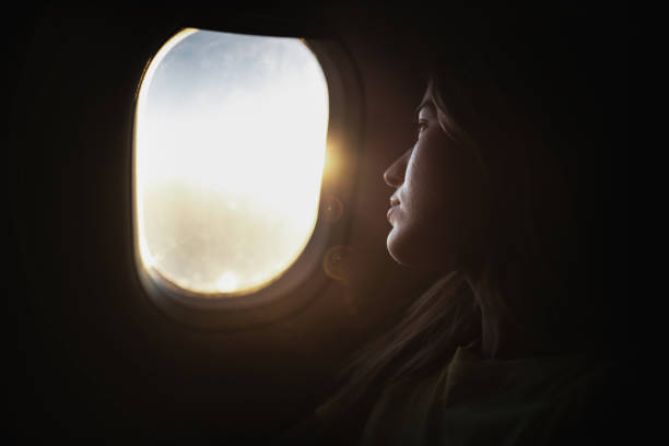 istock Young woman enjoying while looking through airplane window. 1200476909