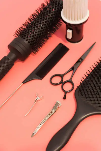 Flat lay composition with hairdresser set on pink background. Barber set with tools and equipment: scissors, combs and hairclips. Hairdresser and beauty salon service.
