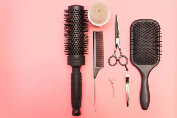 Flat lay composition with hairdresser set on pink background. Barber set with tools and equipment: scissors, combs and hairclips with copy space for text in left. Hairdresser and beauty salon service.