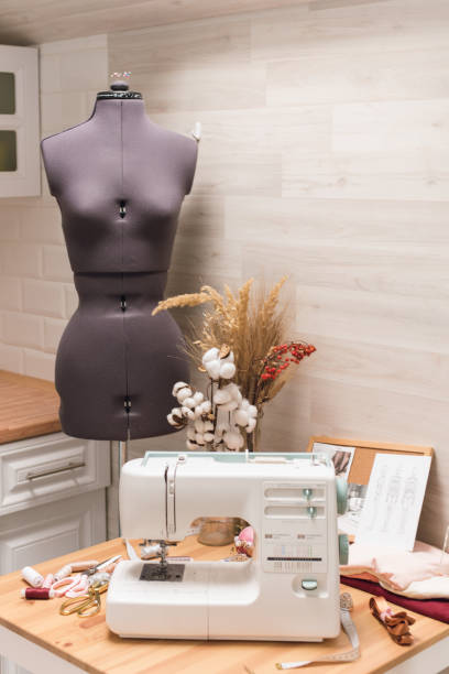 istock The workplace of a seamstress. Sewing machine on the table, thread, scissors and mannequin 1200480001