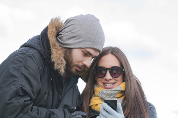 istock Couple using cellphone in cold winter times outdoors. 1200482498