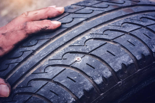 istock Hands on flat car tire punctured with a screw closeup 1200483116