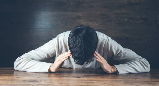 istock sad man hand on head on dark background 1200488269
