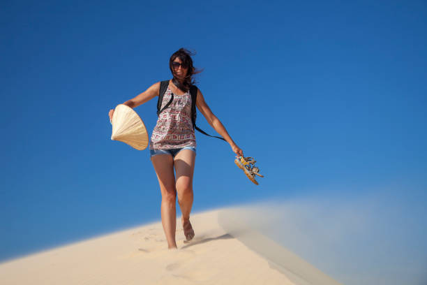 beautiful girl in the desert goes on a hill barefoot on the sand with a hat and shoes in her hands beautiful girl in the desert goes on a hill barefoot on the sand with a hat and shoes in her hands hot vietnamese women pictures stock pictures, royalty-free photos & images