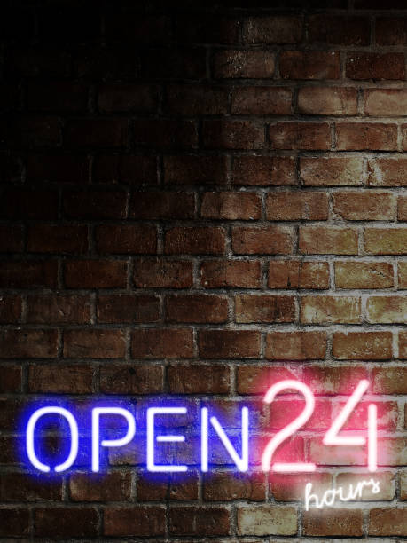 istock Open 24 hours in 7 days sign on rusty brick wall with copy space in vertical. Bar open light Neon Sign. Night store blue, red and white glowing letters. 1200489777