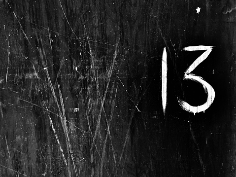 A black and white photo of the number 13 painted on a wall.