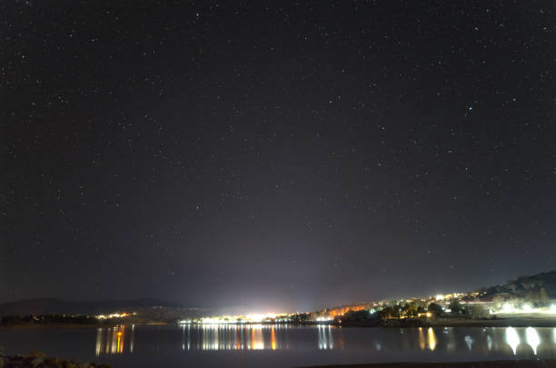 istock Stars arcing over a leafless tree on the shore of Lake Jindabyne 1200492210