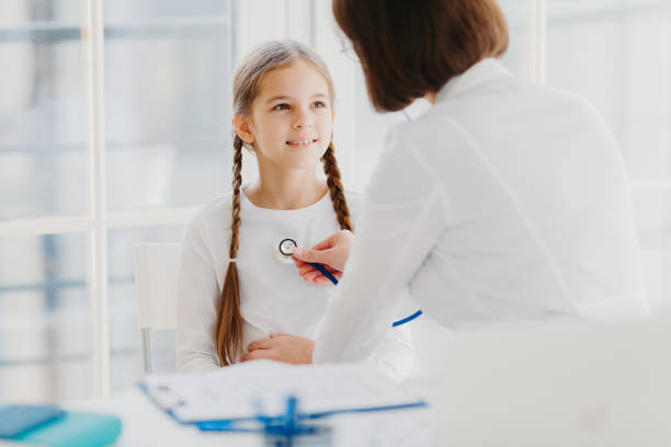 istock Family general practitioner examines child, listens lungs with stethoscope, makes prescription pose in moren hospital office. Ill kid has cold, comes to pediatrician for good advice has health checkup 1200492360