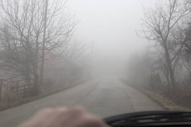 Driving car on foggy winter day. Personal perspective of driver. Photo is taken with full frame camera through windshield on foggy winter day. slippery unrecognizable person safety outdoors stock pictures, royalty-free photos & images