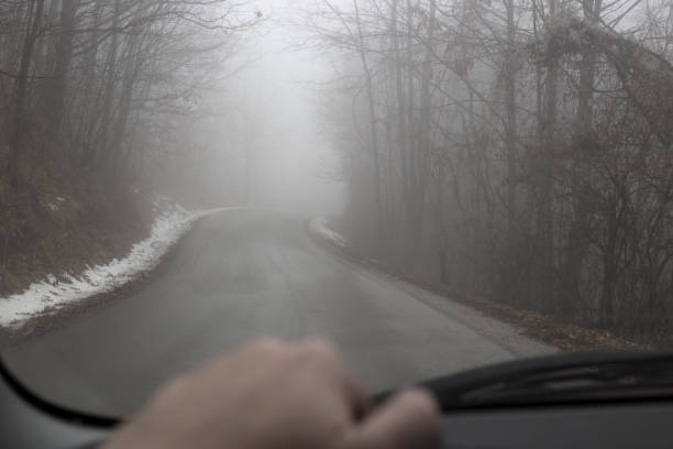 Driving car on foggy winter day. Personal perspective of driver. Photo is taken with full frame camera through windshield on foggy winter day. slippery unrecognizable person safety outdoors stock pictures, royalty-free photos & images