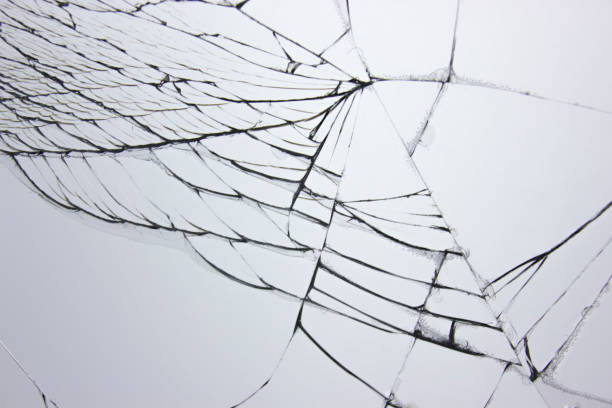 istock Cracked broken glass in window on light gray background. Cracks concept for design. 1200497368