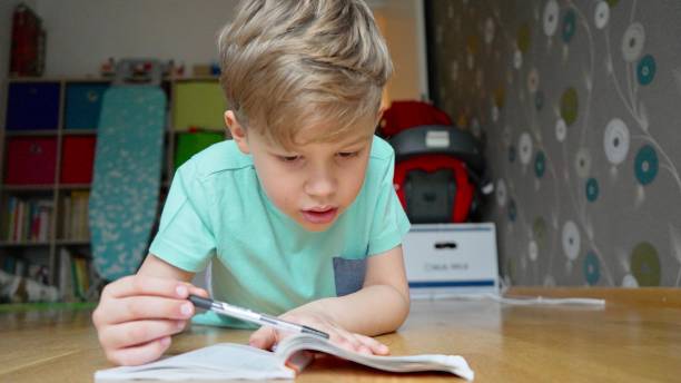 istock Boy concentrating and thinking. Child studying homework and writing in his notebook. Doing math. 1200498446
