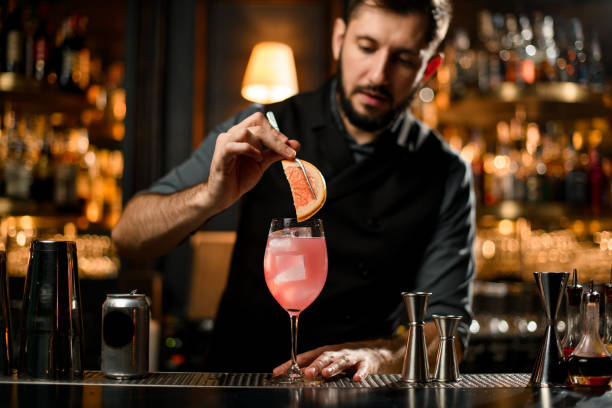 bartender adding grapefruit slice in a drink - men elegance cocktail cool imagens e fotografias de stock