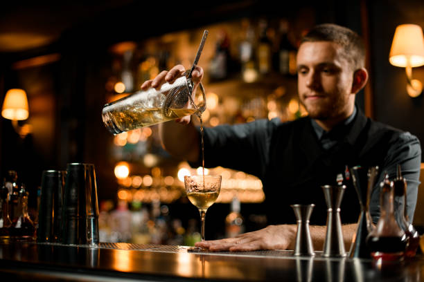 istock Bartender with facial hair pours drink with strainer 1200498806