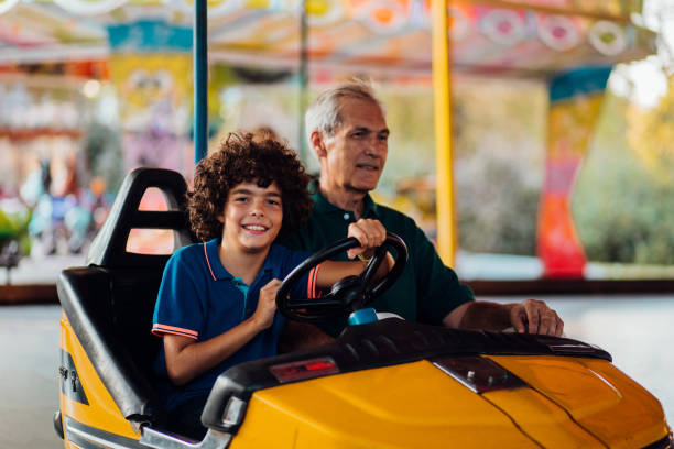 istock Boy driving a bumper car with his grandpa 1200499494