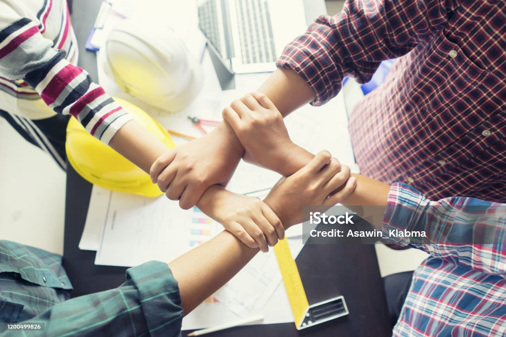 Stack hands of business engineering teamwork join together,construction engineer working in construction site, construction engineer conceptual,architect drawing on architectural project on background Construction Industry Stock Photo