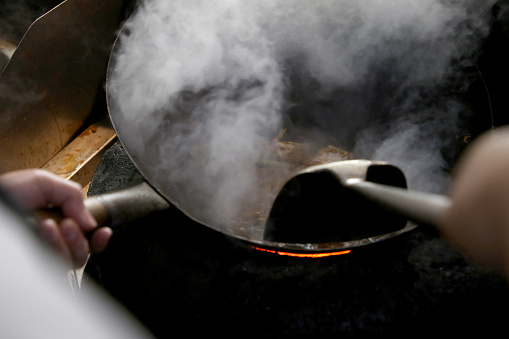 A closer scene on wok at charcoal fireplace in Kuala Lumpur commercial kitchen, Malaysia.