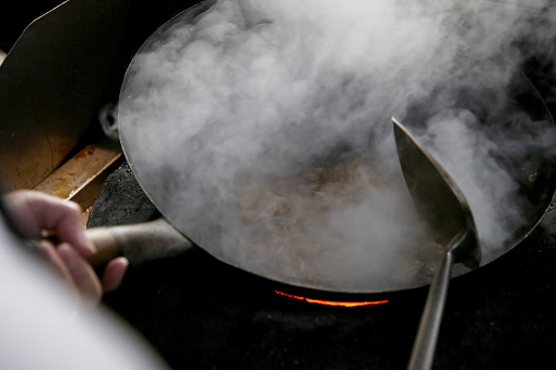 A closer scene on wok at charcoal fireplace in Kuala Lumpur commercial kitchen, Malaysia.